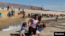 میکسکو - امریکہ کی سرحد پر اکھٹے ہونے والے تارکین وطن اشک آور گیس سے بچنے کے لیے بھاگ رہے ہیں۔ 25 نومبر 2018